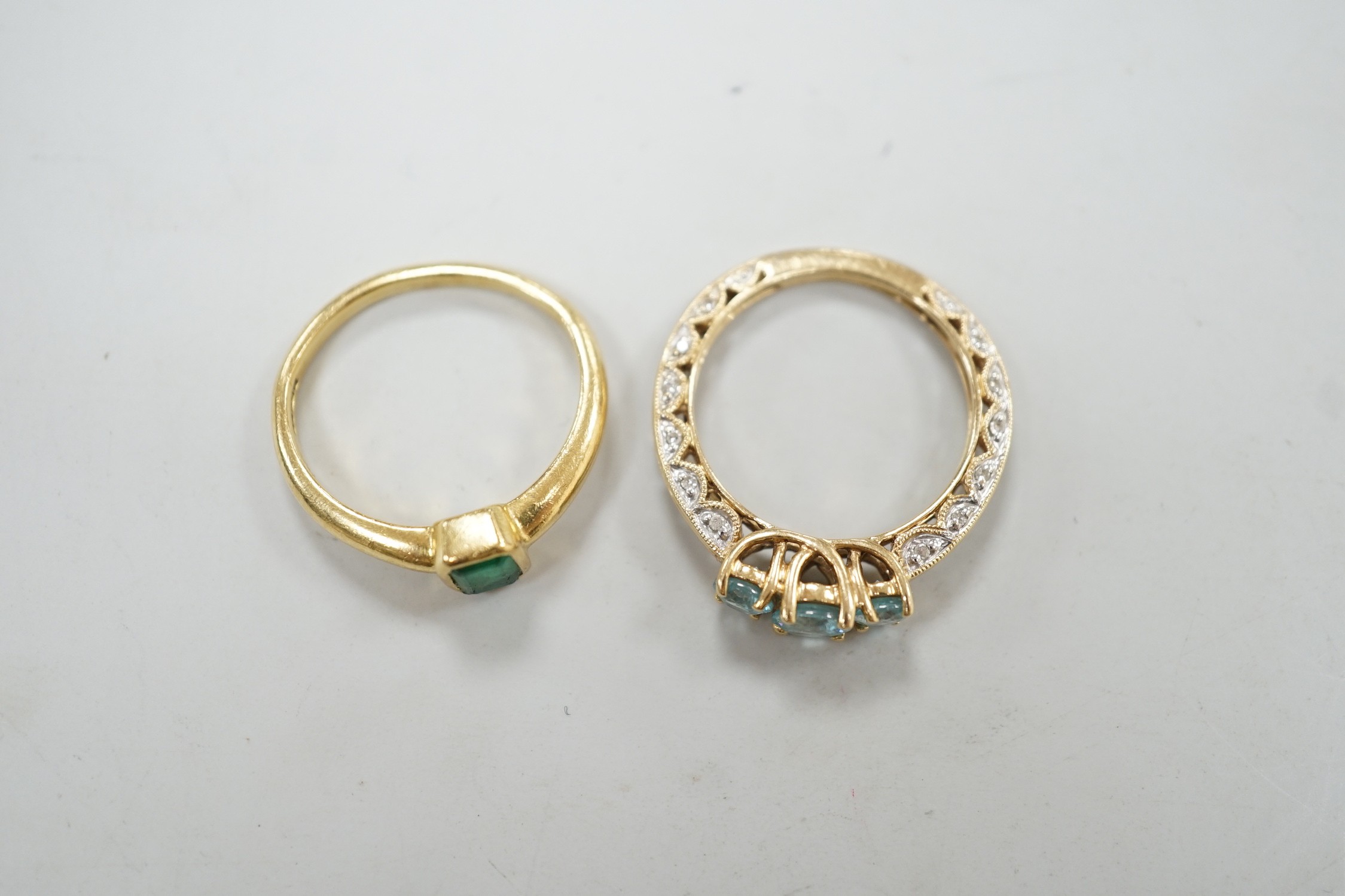 A modern 18ct gold and single stone emerald set ring, size M, gross weight 4 grams and a modern 14k and three stone blue zircon dress ring, with diamond chip set shank, size P, gross weight 3.4 grams.